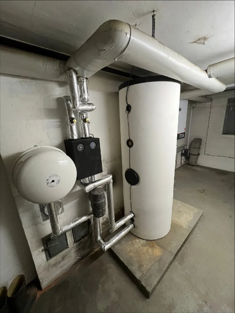 Technikraum mit Speicher und gedämmten Leitungen einer Heizungsanlage.