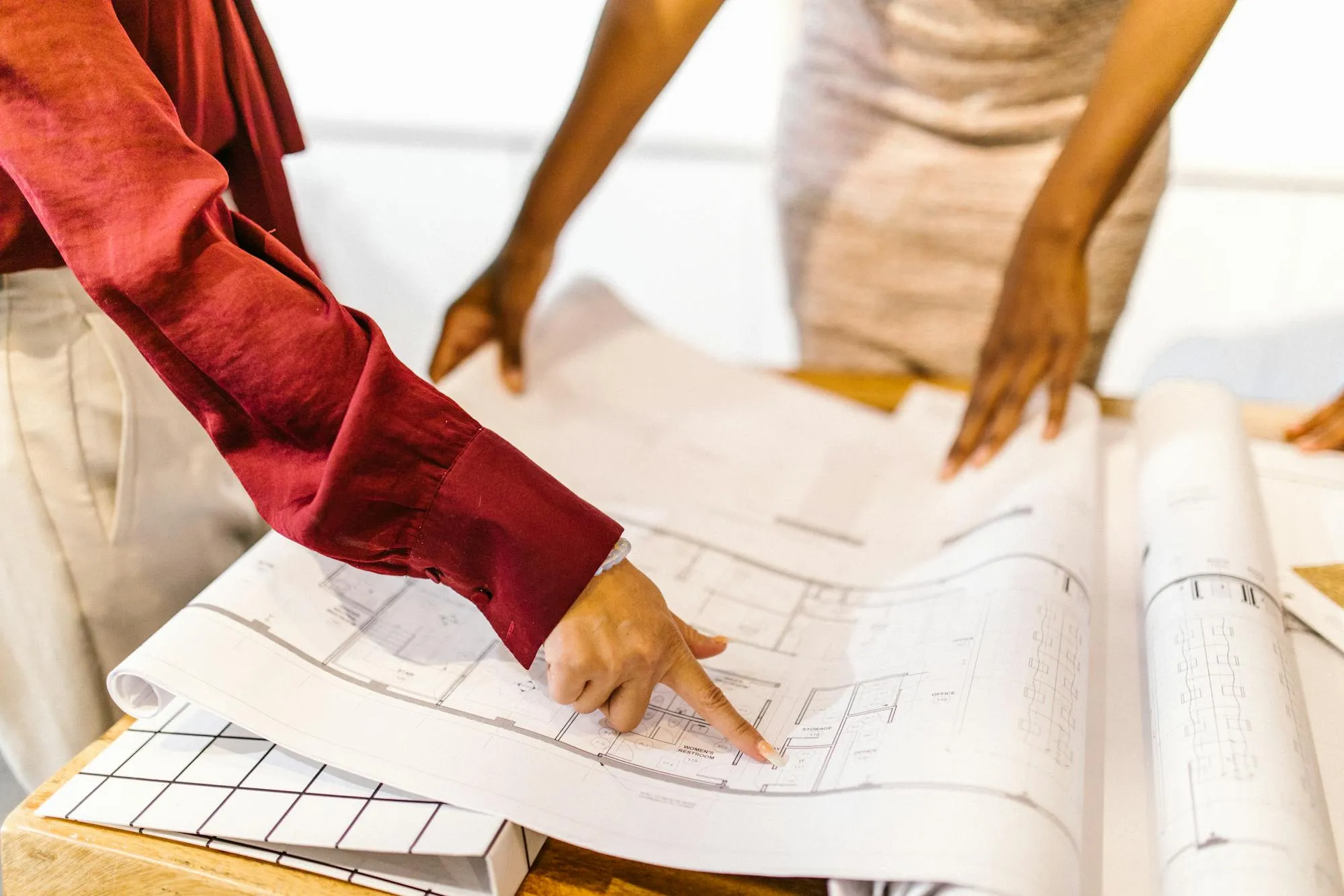Zwei Architektinnen besprechen einen Hausgrundriss am Tisch — symbolisch für die individuelle Anlagenplanung.